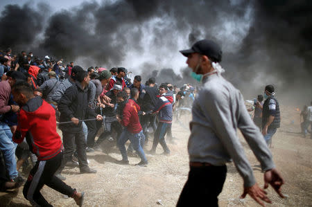 Palestinian demonstrators remove part of the Israeli barbed wire during clashes with Israeli troops at a protest demanding the right to return to their homeland, at the Israel-Gaza border, east of Gaza City, April 13, 2018. REUTERS/Mohammed Salem