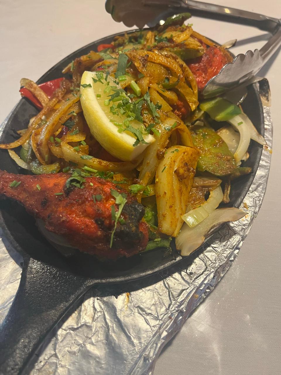 A half order of Tandoori chicken comes sizzling on a hot skillet, marinated with yogurt, ginger garlic and Indian spices for 12 hours at The Spice Delight.
