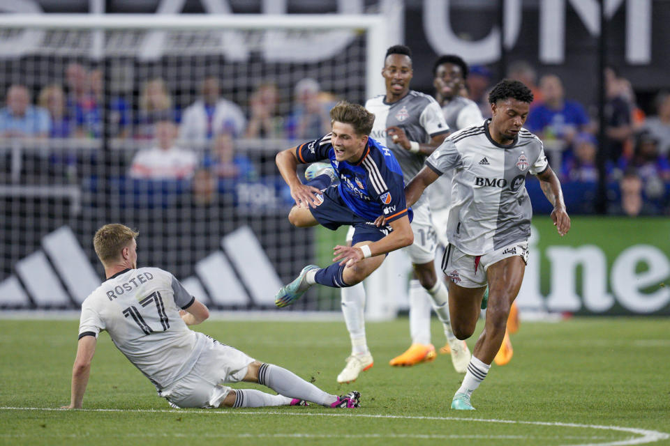 FC Cincinnati's Bret Halsey, center, is tackled by Toronto FC's Sigurd Rosted (17) during the second half of an MLS soccer match Wednesday, June 21, 2023, in Cincinnati. (AP Photo/Jeff Dean)