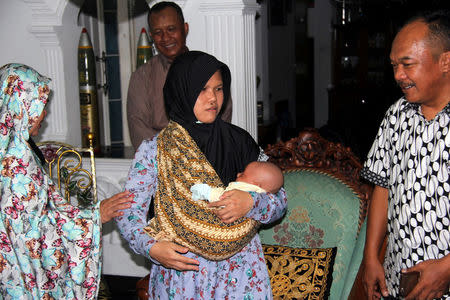 Ernawati, wife of Persatuan Islam (PERSIS) leader Prawoto, holds his baby during an interview with Reuters in Bandung, Indonesia February 20, 2018. Picture taken February 20, 2018. REUTERS/Tom Allard