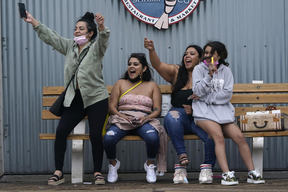 FILE - In this Thursday, May 13, 2021, file photo, visitors react after seeing a friend arrive on the pier in Santa Monica, Calif. California's top health official says the state will no longer require social distancing and will allow full capacity for businesses when the state reopens on June 15. State health director Dr. Mark Ghaly said Friday, May 21, that the state envisions loosening many of its rules in mid-June as coronavirus cases continue to fall and vaccine rates continue to rise. (AP Photo/Marcio Jose Sanchez, File)