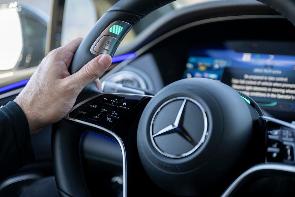 A close-up of the Mercedes-Benz steering wheel with Drive Pilot button. 