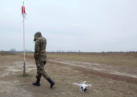 A Ukrainian serviceman walks past a drone during a training session outside Kiev, November 6, 2014. REUTERS/Valentyn Ogirenko