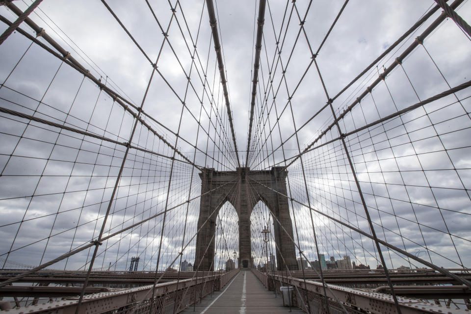 The Brooklyn Bridge walkway is empty of pedestrians and cyclists, Friday, April 10, 2020, in New York. The new coronavirus causes mild or moderate symptoms for most people, but for some, especially older adults and people with existing health problems, it can cause more severe illness or death. (AP Photo/Mary Altaffer)