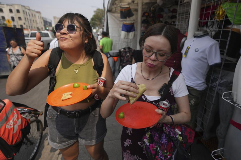 A customer flashes a thumbs up while eating a taco from the Tacos El Califa de León taco stand, in Mexico City, May 15, 2024. Tacos El Califa de León is the first ever taco stand to receive a Michelin star from the French dining guide. (AP Photo/Fernando Llano)