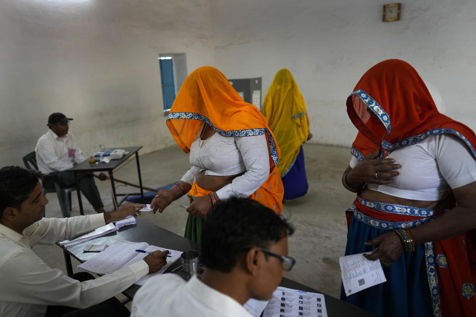 Women show their election cards before casting their votes during the first round of voting of India's national election in Behror, Rajasthan state, India, Friday, April 19, 2024. Nearly 970 million voters will elect 543 members for the lower house of Parliament for five years, during staggered elections that will run until June 1. (AP Photo/Manish Swarup)