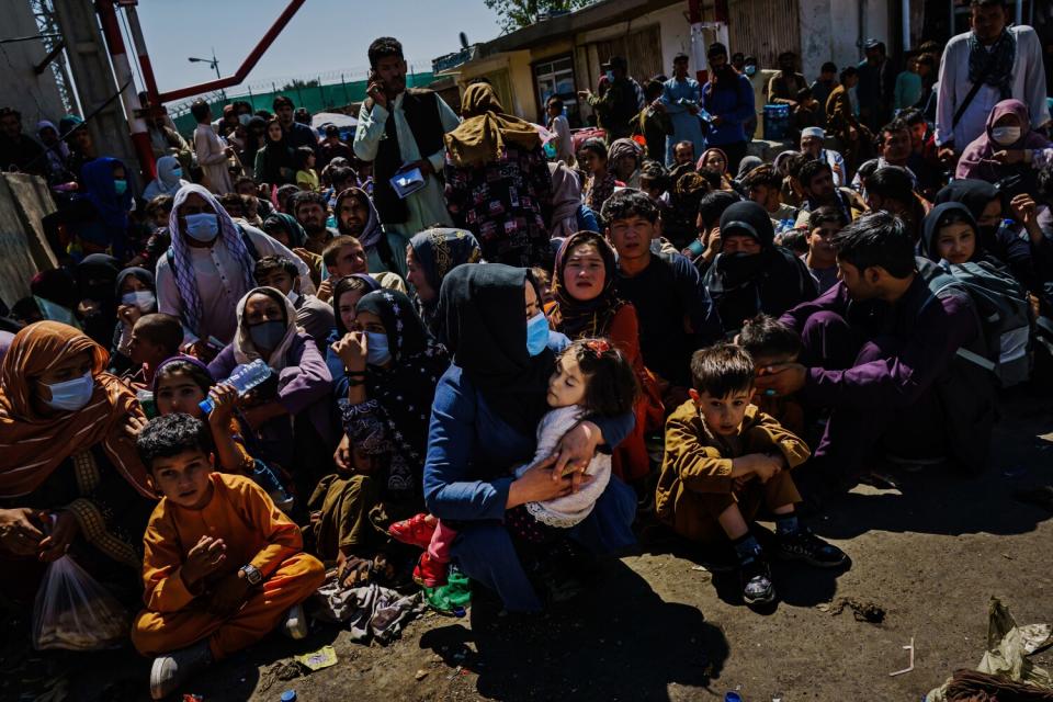 Afghani women and children sit and wait at a checkpoint.