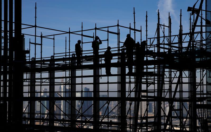 Construction workers are silhouetted while standing on scaffolding at the construction site of the new headquarters of the ECB during a guided media tour in Frankfurt