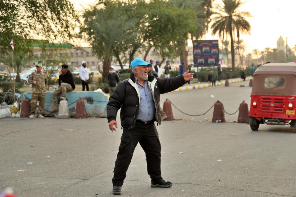 A member of Saraya Salam (Peace Brigades) militia stands guard on a street leading to Tahrir Square where ongoing anti-government protests are taking place in Baghdad, Iraq, Sunday, Dec. 8, 2019. Iraqi security forces on Sunday have set up checkpoints manned alongside unarmed members of a militia group, Iraqi police officials said, to protect anti-government protesters in central Baghdad plazas, days after a deadly attack by unknown gunmen. The militia group are linked to influential Shiite cleric Muqtada al-Sadr, and have been present in Tahrir Square, the epicenter of Iraq's protest movement, where they have offered protection for hundreds of peaceful demonstrators. (AP Photo/Hadi Mizban)