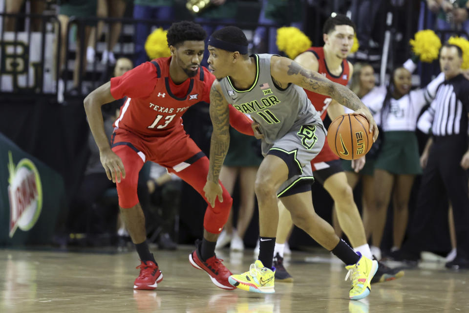 Baylor guard James Akinjo drives against Texas Tech guard Mylik Wilson during the first half of an NCAA college basketball game Tuesday, Jan. 11, 2022, in Waco, Texas. (AP Photo/Jerry Larson)