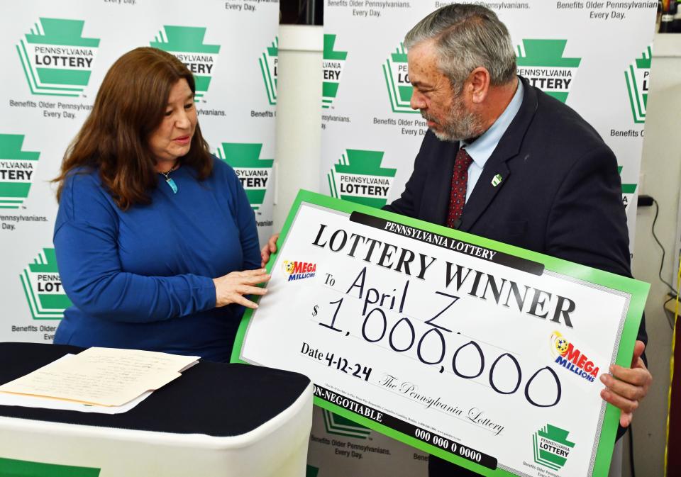 Pennsylvania Secretary of Revenue Pat Browne presents a commemorative check Thursday, April 25, to April Zipp, the winner of a $1 million Mega Millions lottery ticket purchased at BG’s Value Market in Jonestown.