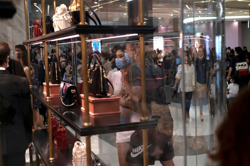 FILE PHOTO: Customers wearing face masks following the coronavirus disease (COVID-19) outbreak, look at the products at a Gucci store, at the Sanya International Duty-Free Shopping Complex, in Sanya