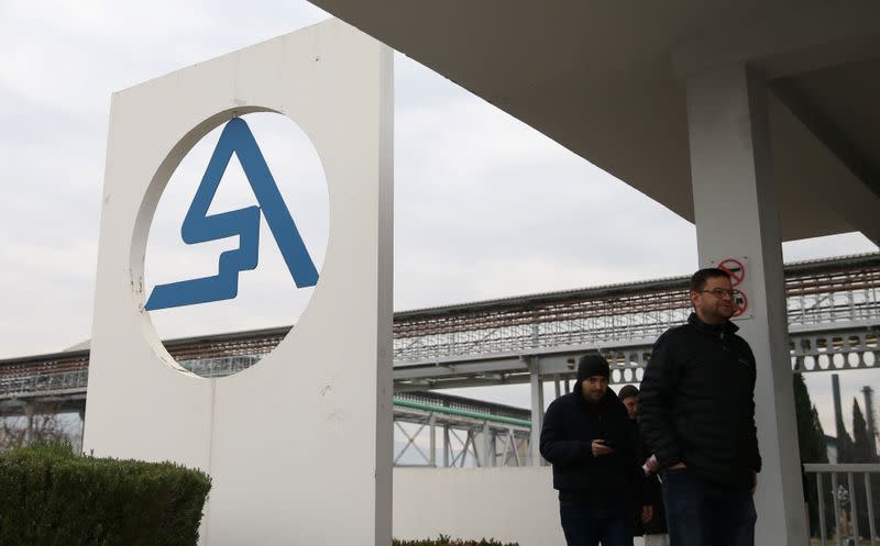 Former workers walk near the logo of the Aluminij Mostar aluminium factory in Mostar