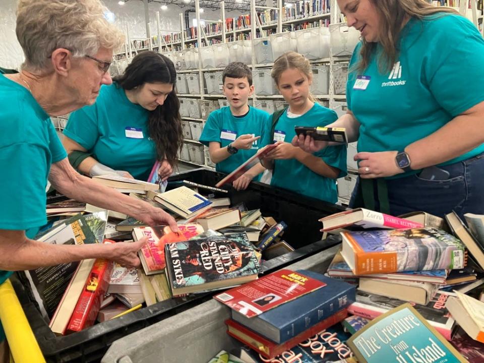 Rachel Mariani (second from left) and her son Vincent (center) hunt for free books to take home after touring the Thriftbooks warehouse in Phoenix on Oct. 20, 2023.