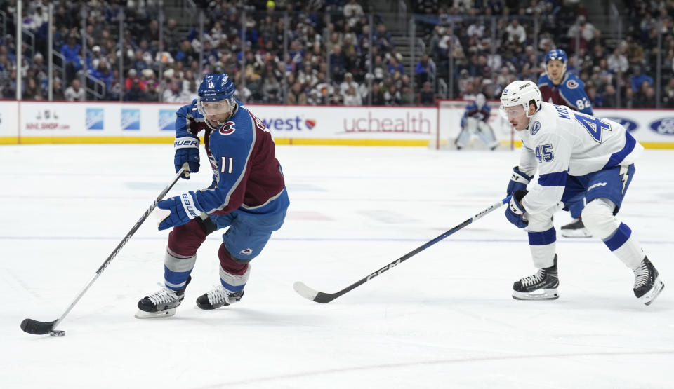 Colorado Avalanche center Andrew Cogliano, left, collects the puck as Tampa Bay Lightning left wing Cole Koepke defends in the first period of an NHL hockey game on Monday, Nov. 27, 2023, in Denver. (AP Photo/David Zalubowski)