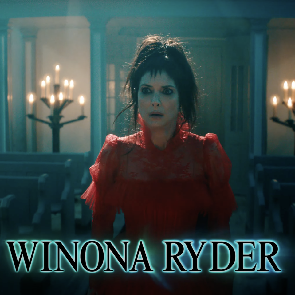 Winona Ryder in a gothic scene, wearing a vintage lace dress, stands in a dimly lit room with candle holders and benches