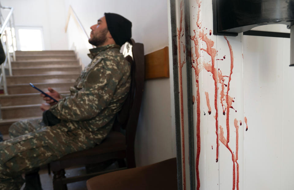 An Armenian serviceman rests near a bloody door in a hospital damaged by shelling from Azerbaijan's artillery in the town of Martakert, the separatist region of Nagorno-Karabakh, Thursday, Oct. 15, 2020. The conflict between Armenia and Azerbaijan is escalating, with both sides exchanging accusations and claims of attacks over the separatist territory of Nagorno-Karabakh.(AP Photo)