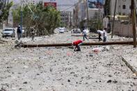 A boy searchs about a toartillery shell in ground at a damaged street, caused by an April 20 air strike that hit a nearby army weapons depot, in Sanaa April 21, 2015. REUTERS/Mohamed al-Sayaghi