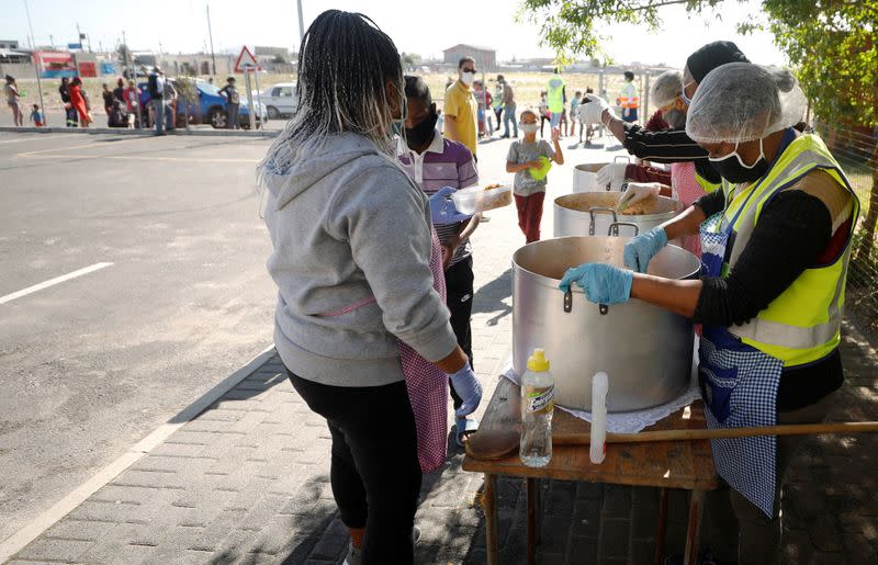 Children queue for food at a school feeding scheme during a nationwide lockdown aimed at limiting the spread of the coronavirus disease (COVID-19) in Blue Downs township near Cape Town