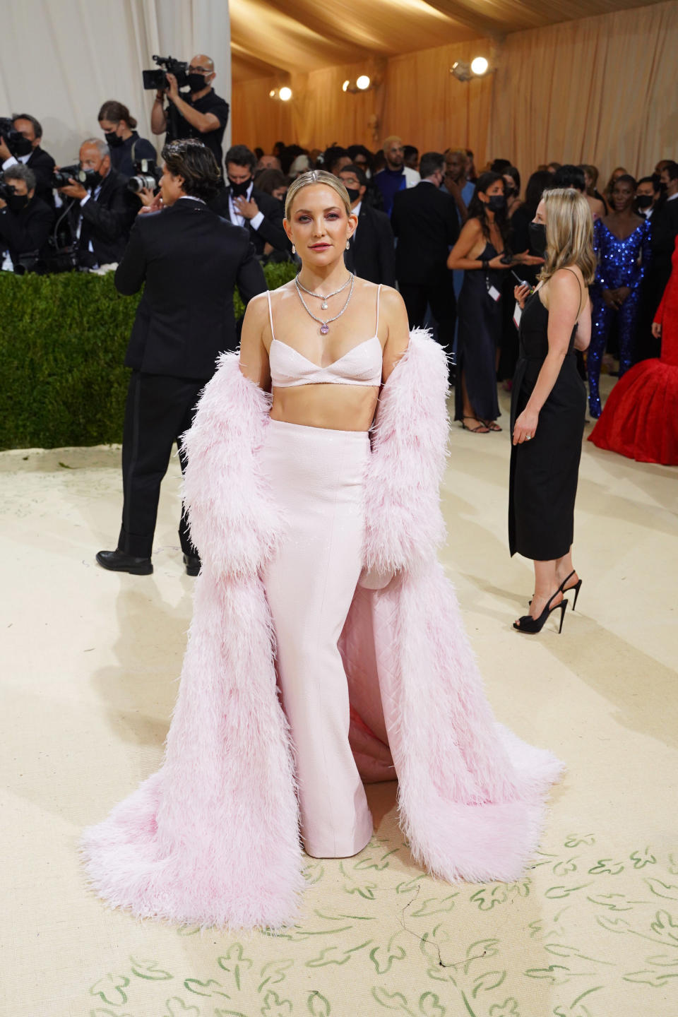 Woman at event in pink outfit with oversized fluffy sleeves and trousers