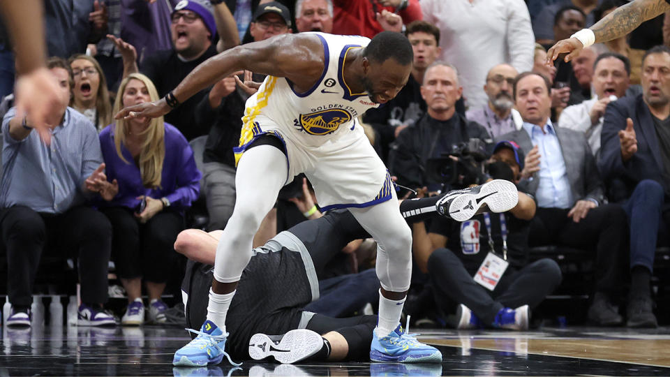 Draymond Green stands over Domantas Sabonis.