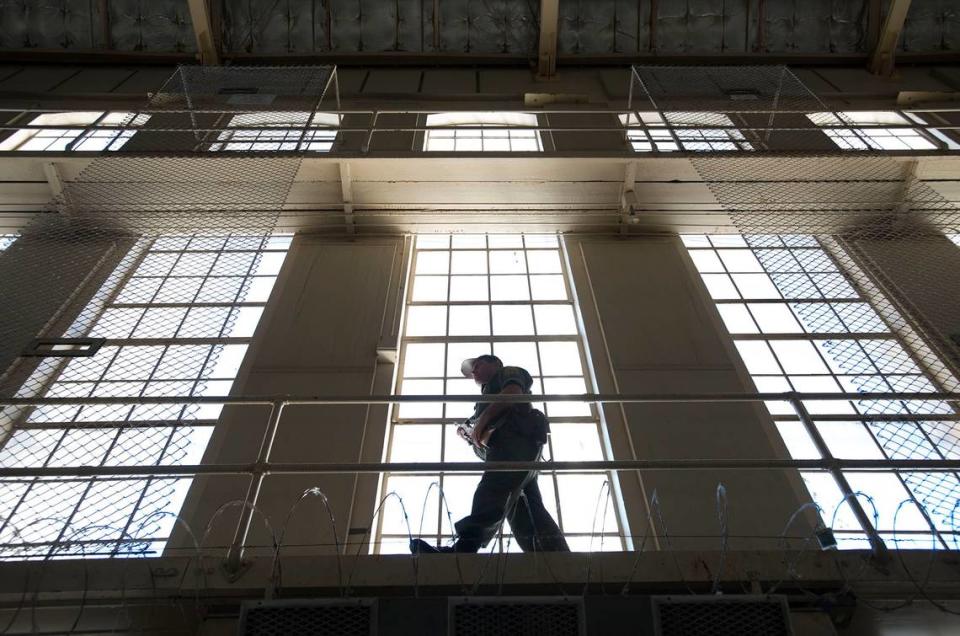 A prison guard carries his weapon while he walks along a catwalk inside East Block at San Quentin State Prison on Tuesday, December. 29, 2015, in San Quentin, Calif.