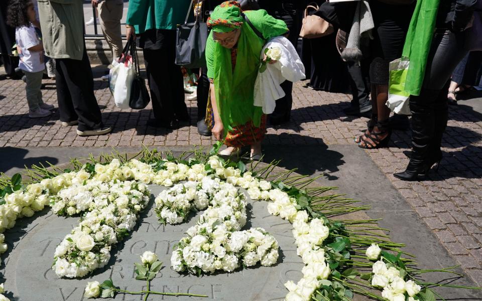 People lay white roses at the memorial outside Westminster Abbey's west door - Jonathan Brady/PA