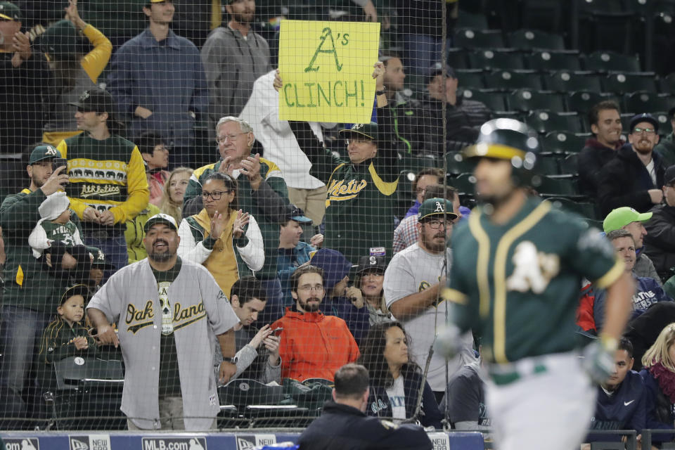 A fan holds a sign that reads "A's Clinch!" as Oakland Athletics shortstop Marcus Semien rounds the bases after hitting a solo home run during the first inning of a baseball game against the Seattle Mariners, Friday, Sept. 27, 2019, in Seattle. The Athletics clinched a wild-card berth in the American League before the first pitch of their game when the Cleveland Indians lost to the Washington Nationals. (AP Photo/Ted S. Warren)
