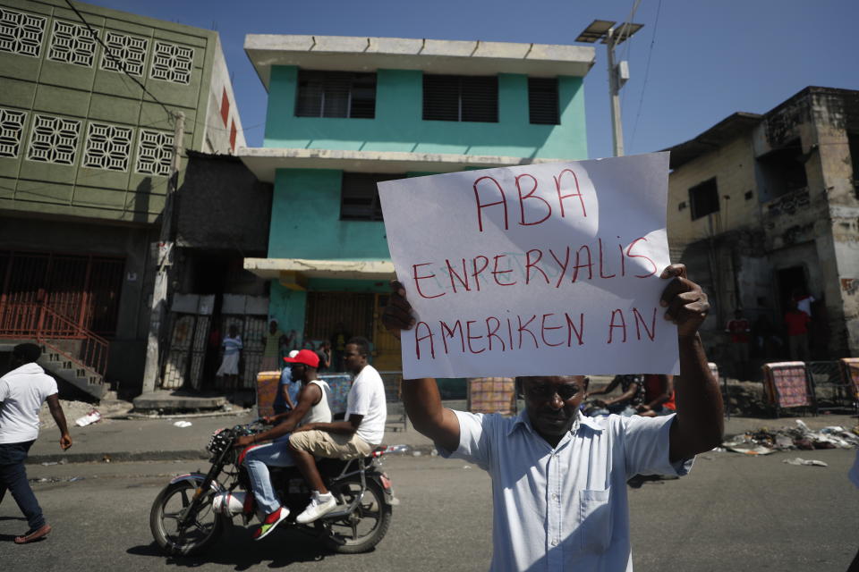A demonstrator holds up the Creole message "Under American imperialism" during a march led by the art community to continue demanding the resignation of Haitian President Jovenel Moise in Port-au-Prince, Haiti, Sunday, Oct. 13, 2019. Protests have paralyzed the country for nearly a month, shuttering businesses and schools. (AP Photo/Rebecca Blackwell)