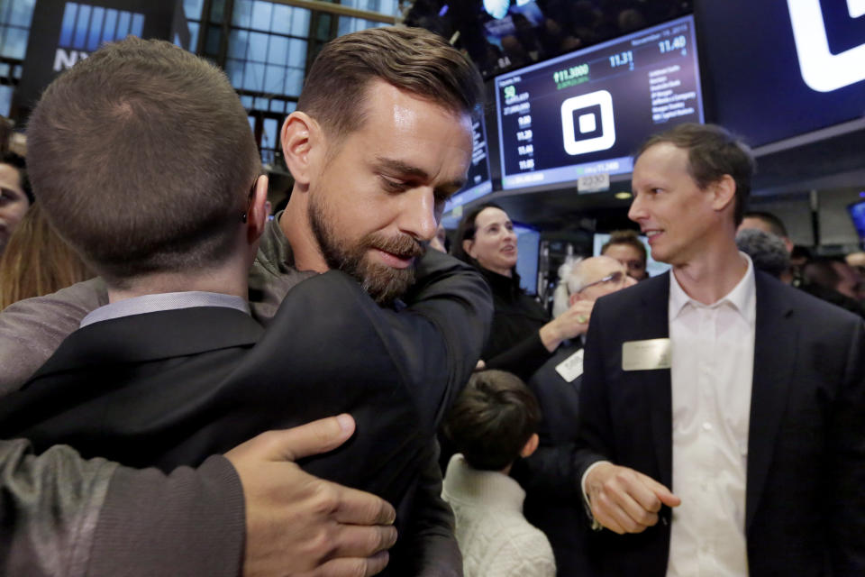 Square CEO Jack Dorsey is hugged on the floor of the New York Stock Exchange after Square began trading on Nov. 19, 2015. Square co-founder Jim McKelvey is at right. (AP/Richard Drew)