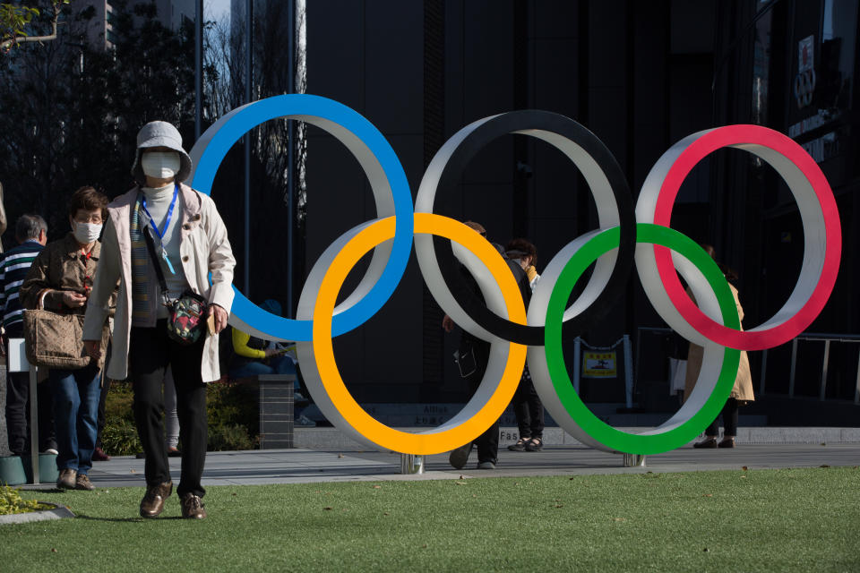 SHINJUKU, TOKYO, JAPAN - 2020/03/19: Women with surgical masks walk next to the Olympic Rings in front of the Japan Olympic Museum in Shinjuku.  Japanese start thinking that it would be the best to postpone the Tokyo 2020 Olympic and Paralympic Games due to the fear of spreading the Covid-19 Coronavirus more into its population. (Photo by Stanislav Kogiku/SOPA Images/LightRocket via Getty Images)