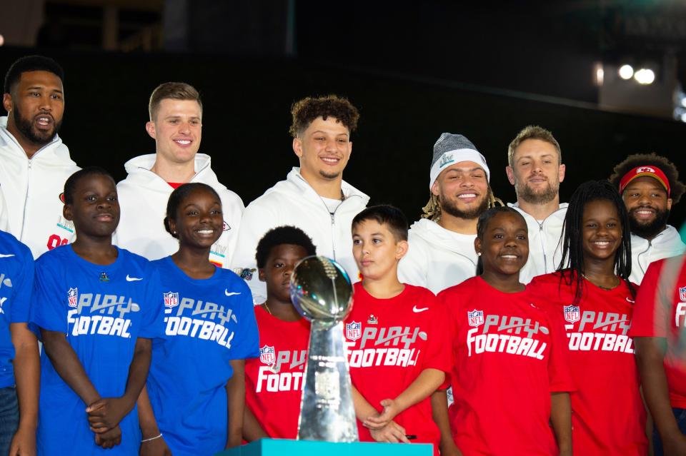 NFL football players, including Patrick Mahome (center, back row) pose with a group of children.