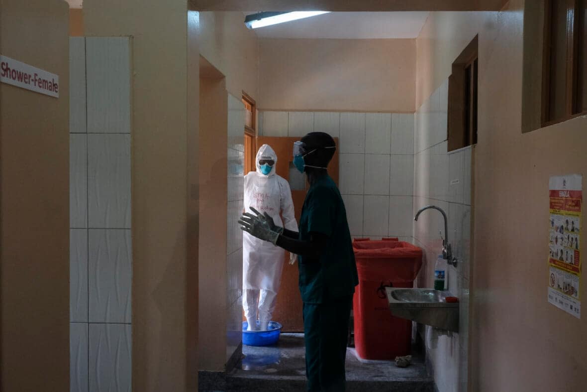 Doctors disinfect themselves after visiting a patient who was in contact with an Ebola victim, in the isolation section of Entebbe Regional Referral Hospital in Entebbe, Uganda on Oct. 20, 2022. (AP Photo/Hajarah Nalwadda, File)