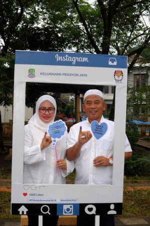 Bekasi mayor candidate Rahmat Effendi (R) accompanied by his wife Gunarti (L) pose for a photograph after voting in Bekasi, West Java, Indonesia June 27, 2018 in this photo taken by Antara Foto. Picture taken June 27, 2018. Antara Foto/Suwandy/via REUTERS