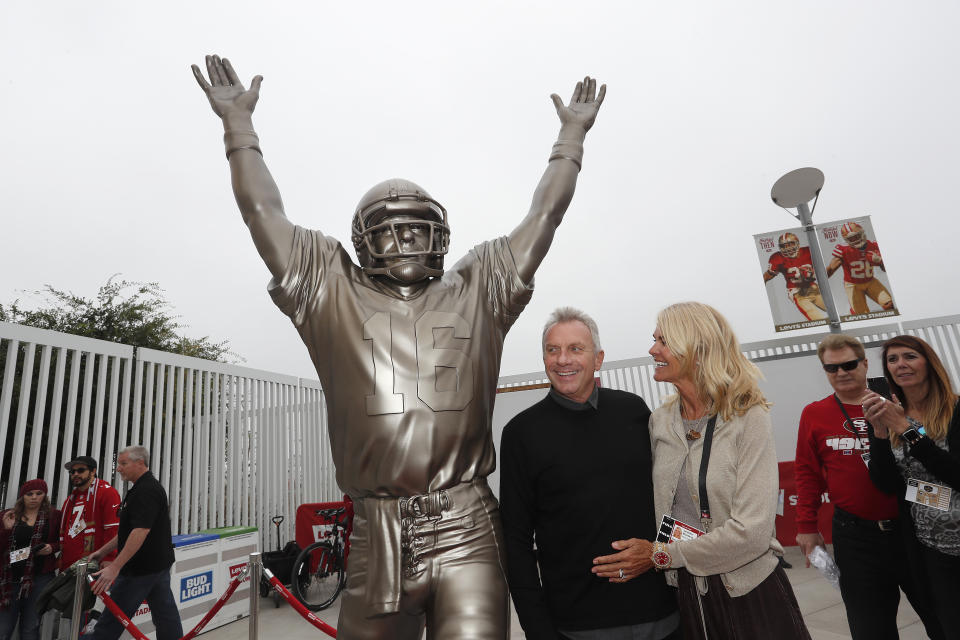 FILE - Former San Francisco 49ers quarterback Joe Montana, center, and his wife Jennifer pose for photos next to a statue of Montana commemorating "The Catch," which was unveiled along with a statue of wide receiver Dwight Clark, before an NFL football game between the 49ers and the Los Angeles Rams in Santa Clara, Calif., Sunday, Oct. 21, 2018. The 19-foot, 4,000-pound statue of Kobe Bryant in downtown Los Angeles is just the latest example of a sports team honoring a player with this kind of larger-than-life presence. (AP Photo/Tony Avelar, File)