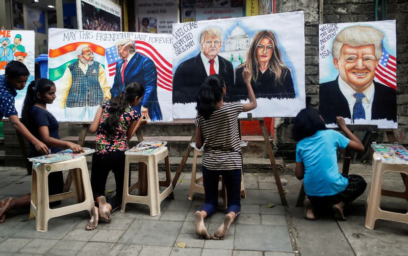 Students paint murals of U.S. President Donald Trump and first lady Melania Trump on canvas sheets along a street in Mumbai
