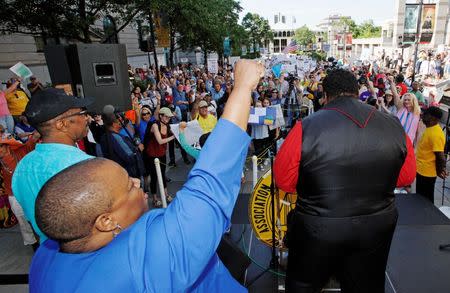 Bishop Tonyia Rawls, the openly gay pastor of Charlotte's Sacred Souls Community Church and founder of The Freedom Center for Social Justice, raises her fist as the Reverend Doctor William Barber II (R), president of the NAACP's North Carolina chapter and leader of the "Moral Monday" civil rights protests, speaks against the state's HB2 "bathroom law" that restricts members of the LGBT community from using the bathroom of their choice, during a demonstration outside the state legislature in Raleigh, North Carolina on May 16, 2016. REUTERS/Jonathan Drake