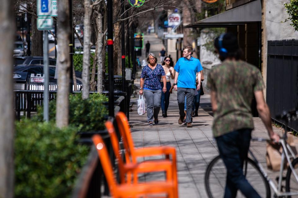 Visitors to downtown Greenville walk down Main Street Friday, March 20, 2020.