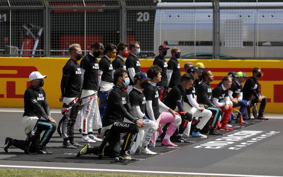 Drivers wearing a Black Lives Matter shirt, takes a knee and stand against racism in the pit lane prior the British Formula One Grand Prix at the Silverstone racetrack, Silverstone, England, Sunday, Aug. 2, 2020. (AP Photo/Frank Augstein, Pool)