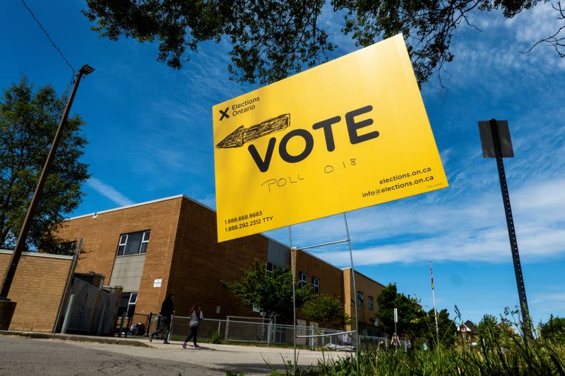 People walk by a vote sign near a polling station during Ontario’s provincial election in Hamilton, Ontario