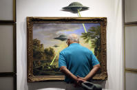 <p>A visitor examines the painting entitled ‘UFO’ by British Banksy is on display at the exhibition ‘The Art of Banksy’ in Berlin, Germany on June 20, 2017. (Felipe Trueba/EPA/REX/Shutterstock) </p>