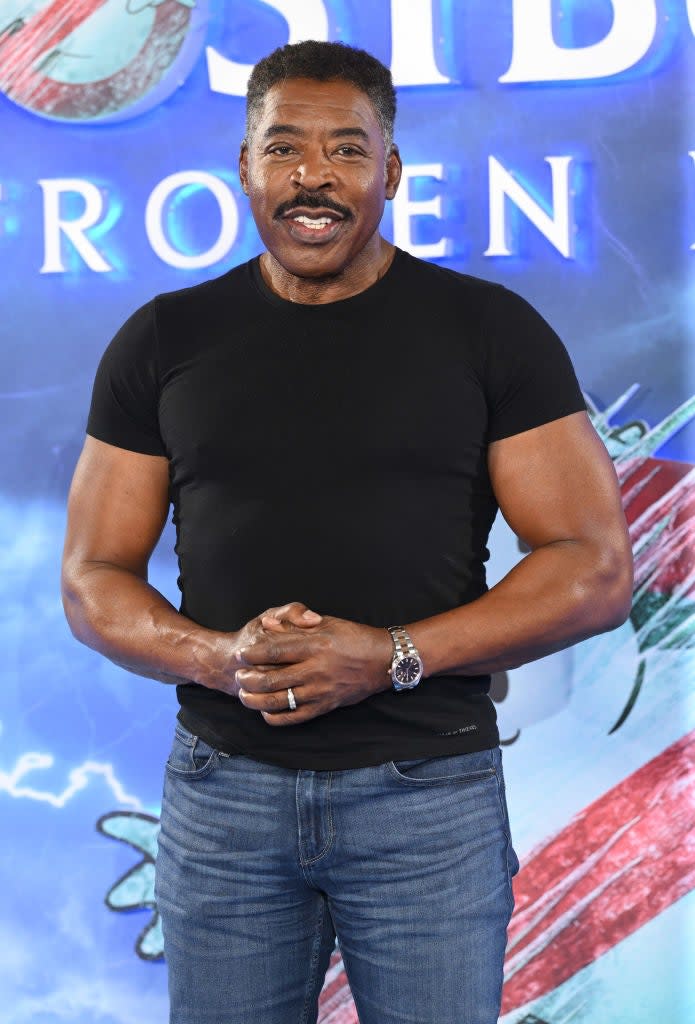 Ernie Hudson poses on the red carpet wearing a black fitted t-shirt and blue jeans at an event