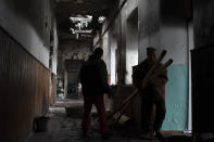 Workers clean up a school that was damaged from Russian shelling in the town of Orekhovo in Zaporizhzhya region, Ukraine, Monday, Jan. 30, 2023. (AP Photo/Andriy Andriyenko)