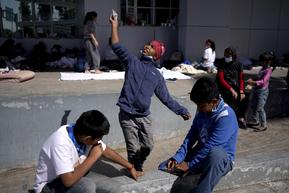 A migrant boy, center, launches a paper airplane while playing with other migrant children at a plaza near the McAllen-Hidalgo International Bridge point of entry into the U.S., after being caught trying to cross into the U.S. and deported, Thursday, March 18, 2021, in Reynosa, Mexico. (AP Photo/Julio Cortez)