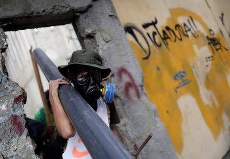 Demonstrators collect materials to build barricades while rallying against Venezuela's President Nicolas Maduro's government in Caracas, Venezuela, August 4, 2017. The graffiti on the wall reads "Dictatorship". REUTERS/Ueslei Marcelino