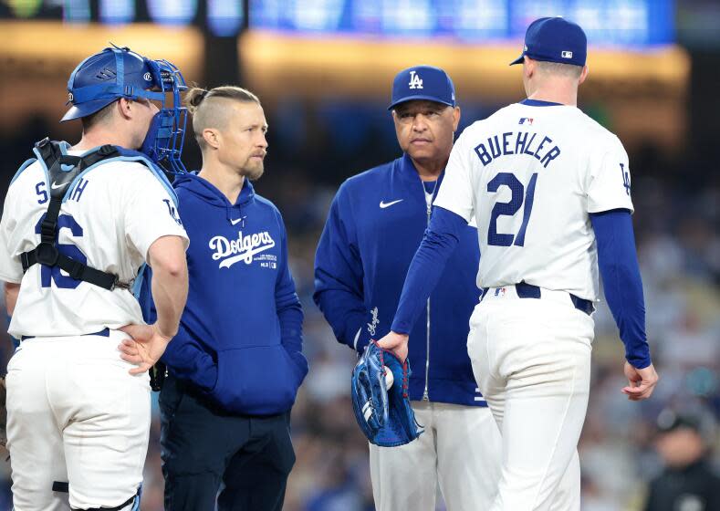 LOS ANGELES CALIFORNIA CALIFORNIA-A Dodgers trainer and manager Dave Roberts check on pitcher Walker Buehler in the fourth inning at Dodgers Stadium Wednesday. (Wally Skalij/Los Angeles Times)