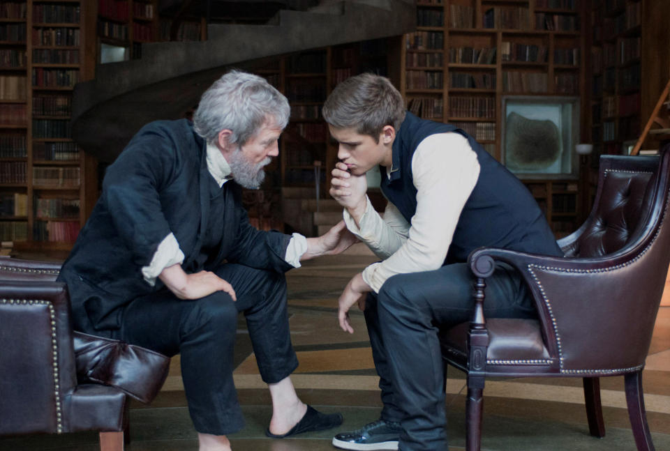 two men sitting on chairs and leaning in to speak to each other