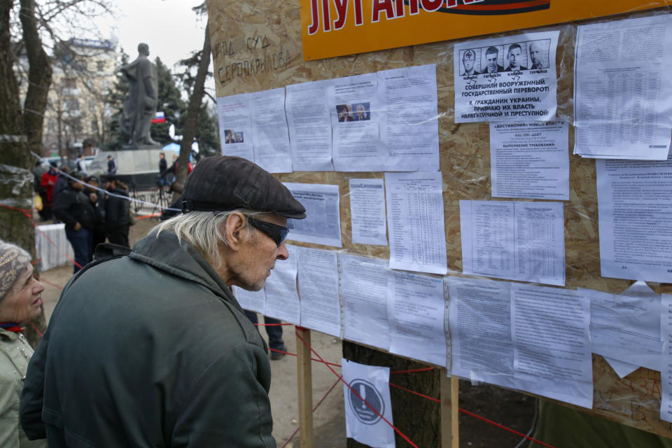 In this photo taken Tuesday, March 11, 2014, people read notices placed on an information board at a pro Russia camp set up in the town of Luhansk, eastern Ukraine, Tuesday, March 11, 2014. In 2010, the year of Ukraine’s last presidential election, Luhansk gave 89% of its votes to Victor Yanukovych, a native of another town in the Donbas coal mining region. (AP Photo/Sergei Grits)