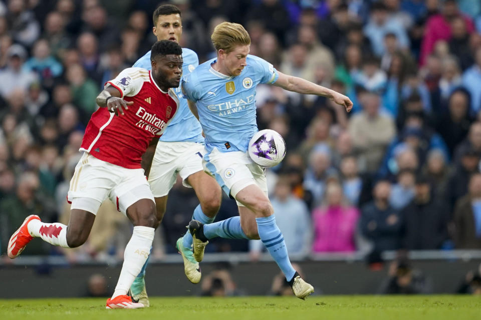 Arsenal's Thomas Partey, left, duels for the ball with Manchester City's Kevin De Bruyne during the English Premier League soccer match between Manchester City and Arsenal at the Etihad stadium in Manchester, England, Sunday, March 31, 2024. (AP Photo/Dave Thompson)