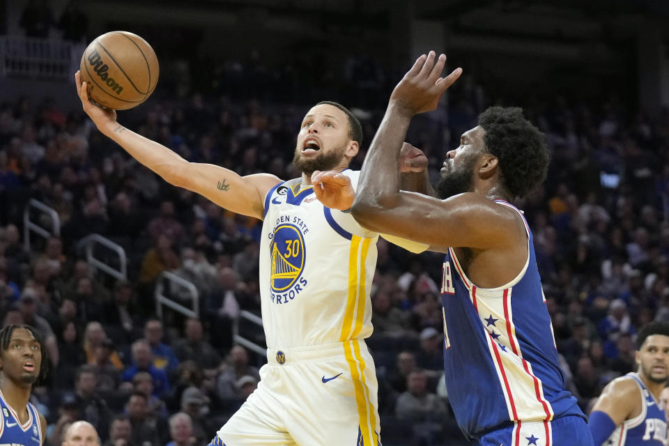 Golden State Warriors guard Stephen Curry (30) scores against Philadelphia 76ers center Joel Embiid during the second half of an NBA basketball game in San Francisco, Friday, March 24, 2023. (AP Photo/Jeff Chiu)